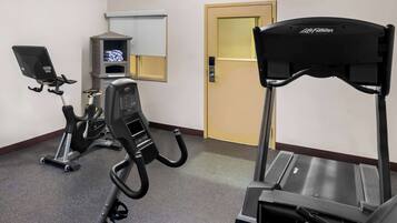 Un gimnasio con cinta de correr, máquina elíptica y bicicleta estática.
