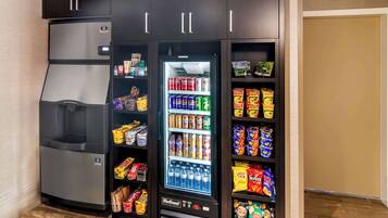 A compact refrigerator with a freezer compartment, a beverage dispenser, and shelves stocked with snacks and beverages.