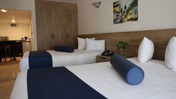 Une chambre d’hôtel avec deux lits, une armoire en bois, un bureau avec une chaise et un tableau au mur.