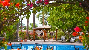 A pool area with lounge chairs and a gazebo.