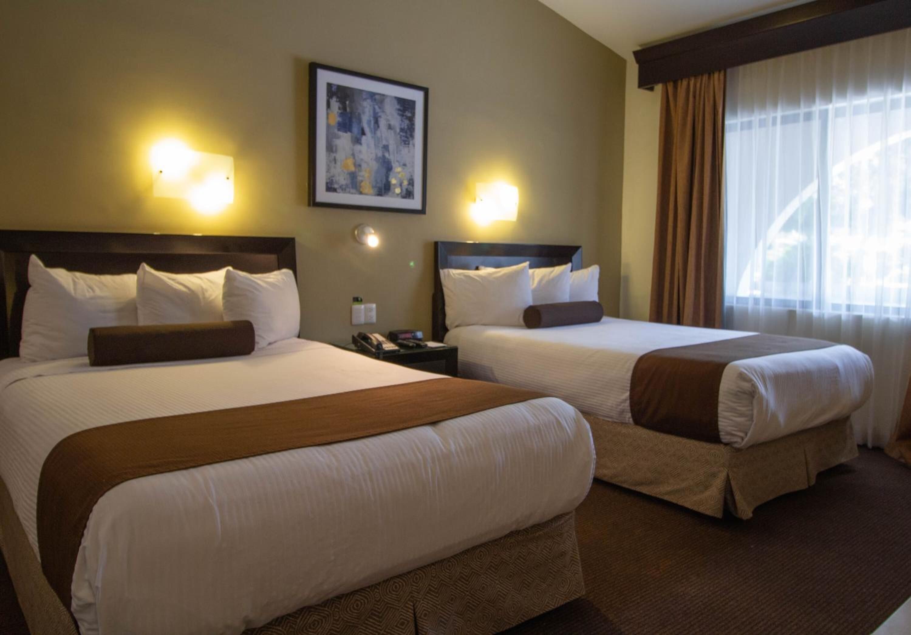 A hotel room with two beds, a nightstand, a phone, and a painting on the wall.