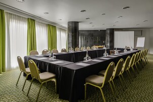A conference room with a long table, chairs, a projector screen, and a whiteboard.