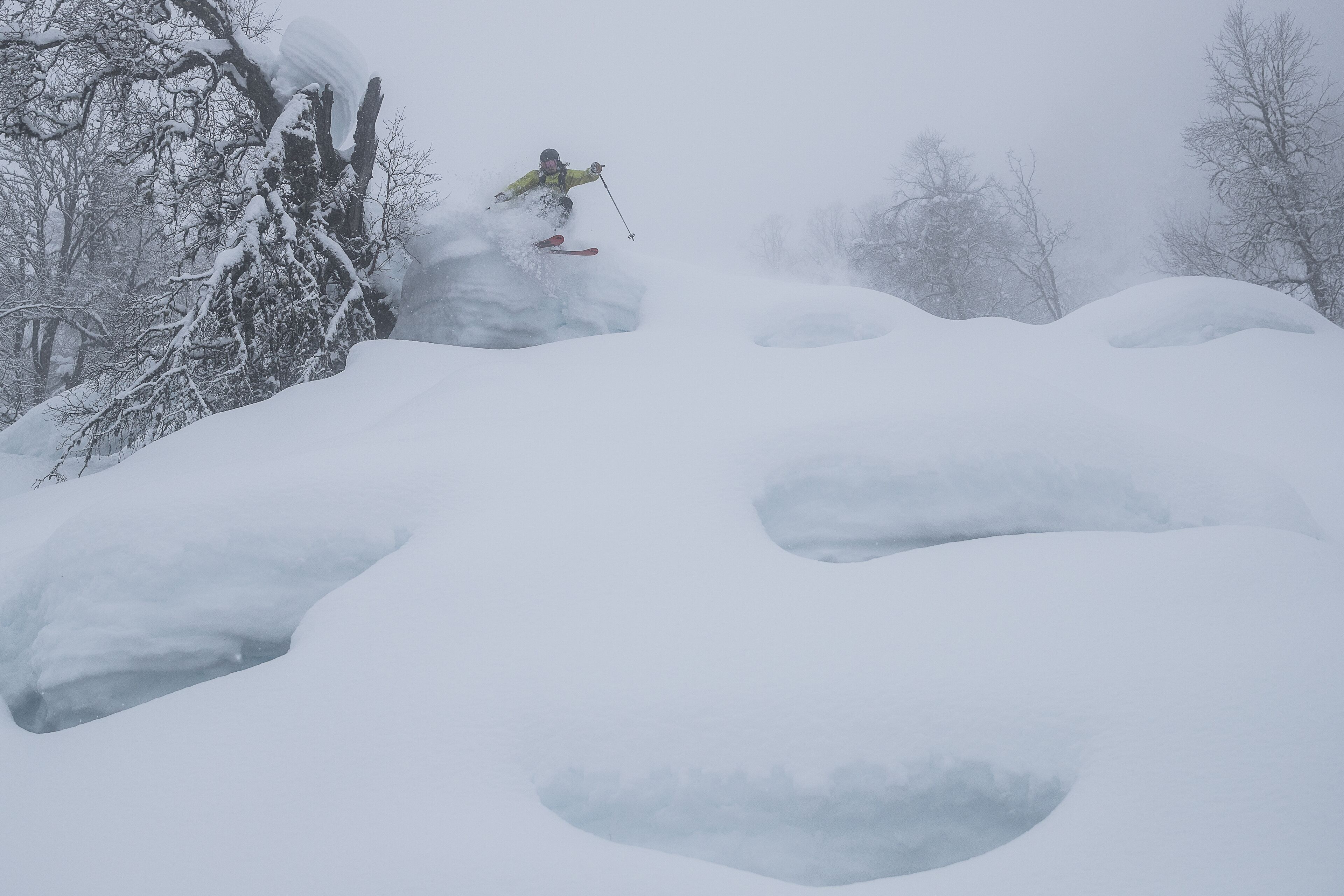 Un paysage enneigé où l’on voit un skieur effectuer un saut.
