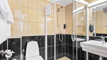 A modern bathroom with a glass-enclosed shower, a white toilet, and a sink with a mirror.