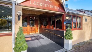 Exterior del Hotel Legreid con una entrada destacada, un felpudo negro con el nombre del hotel y una pequeña planta en maceta junto a la entrada.