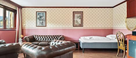 A room with a large brown leather sofa, a bed, and a wooden dresser.