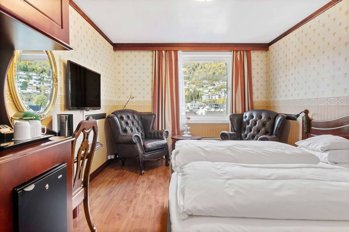Une chambre d’hôtel avec deux lits, une télévision, un bureau avec un ordinateur et une vue sur la ville.