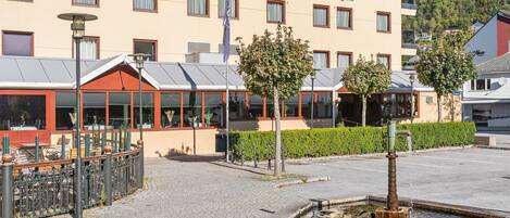 A hotel with a modern facade, outdoor seating area, and a small water feature.