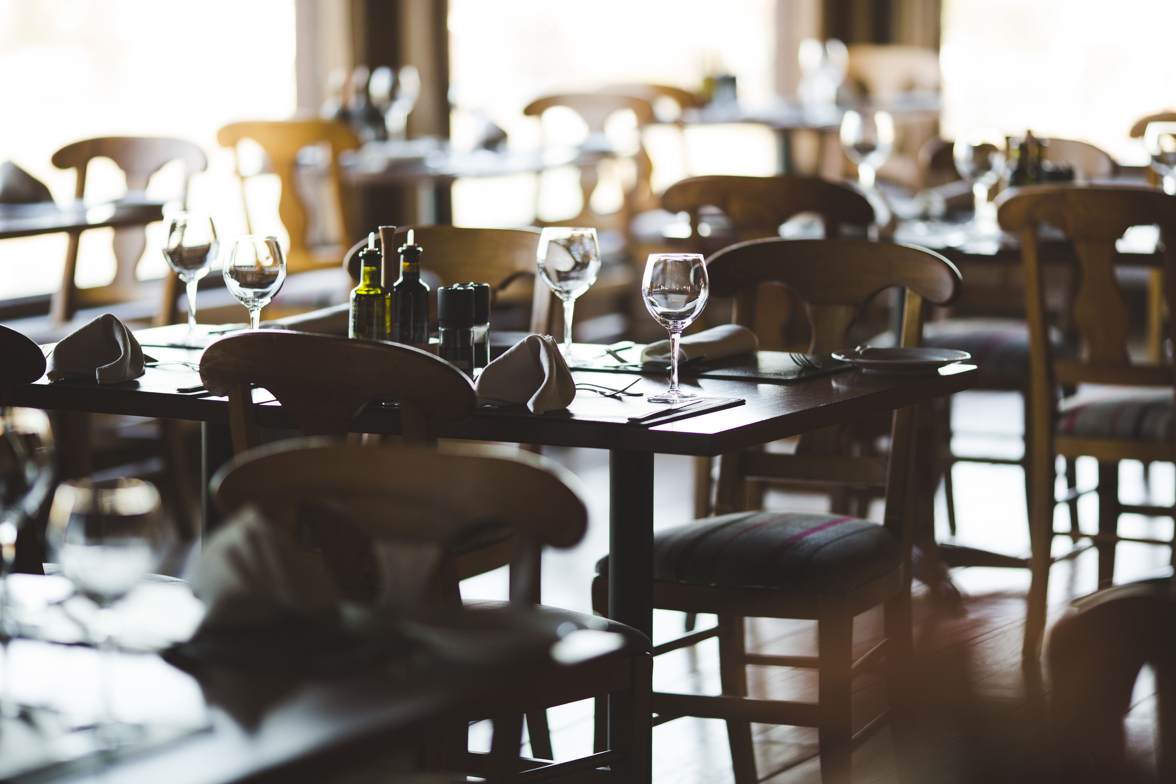 Een restaurant met gedekte tafels, stoelen en wijnglazen.