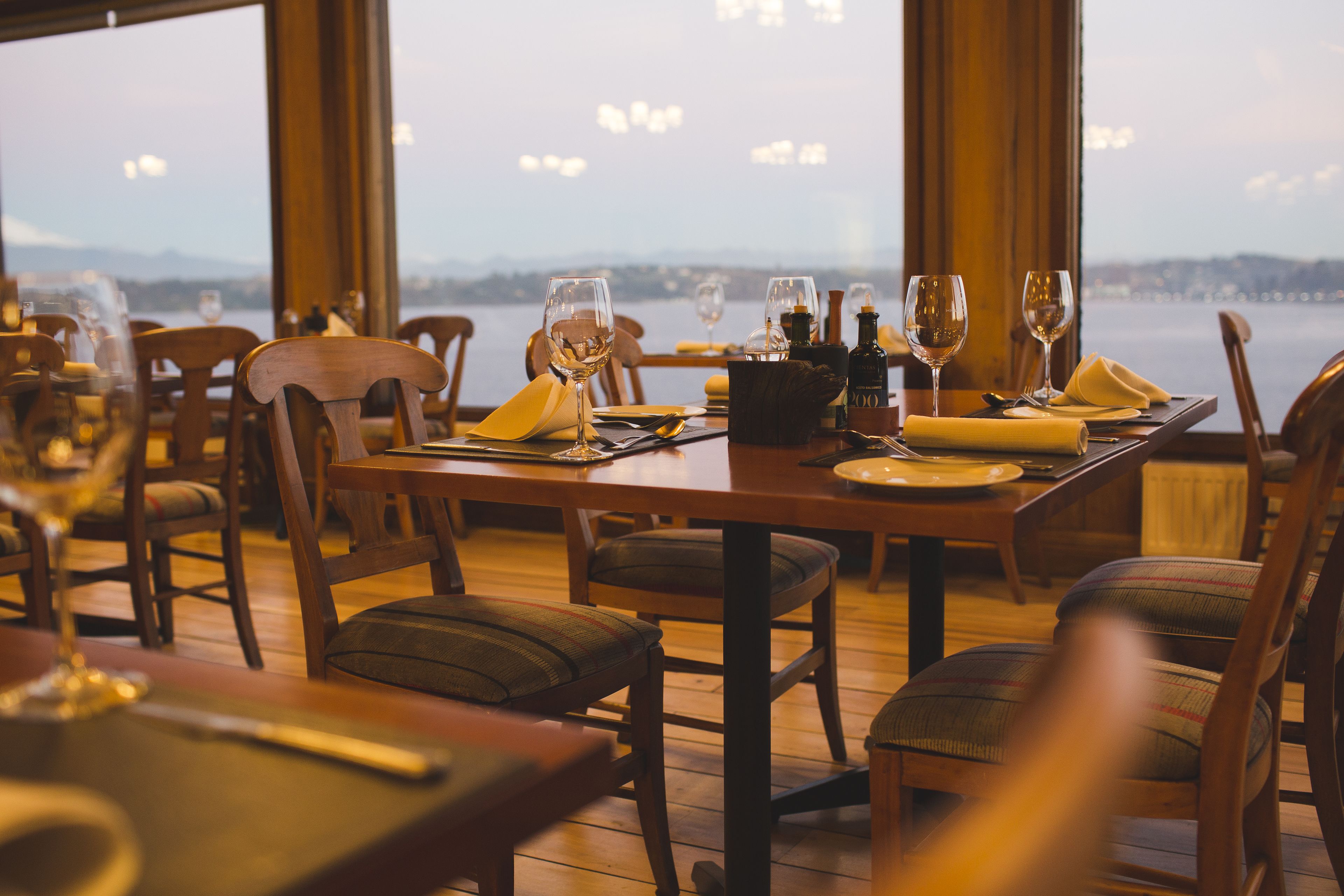 A dining table set for two with wine glasses, a bottle, and a napkin.