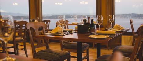 A dining table set for two with wine glasses, a bottle, and a napkin.