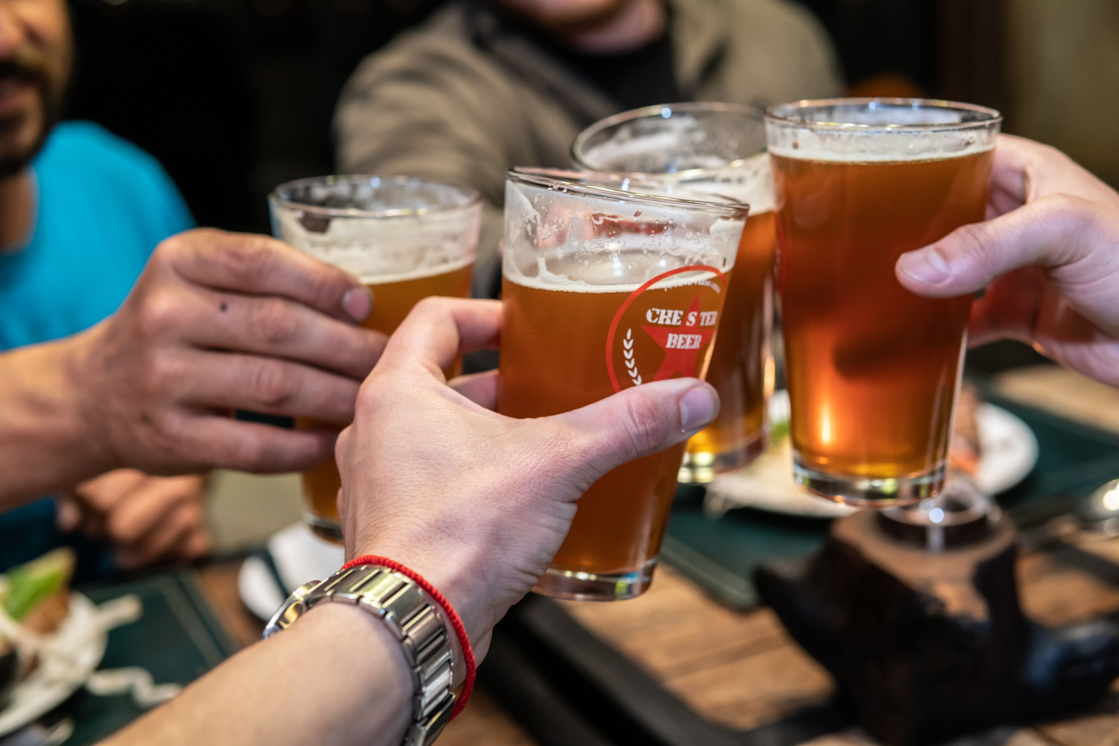 A group of people holding glasses of beer with a logo on them.