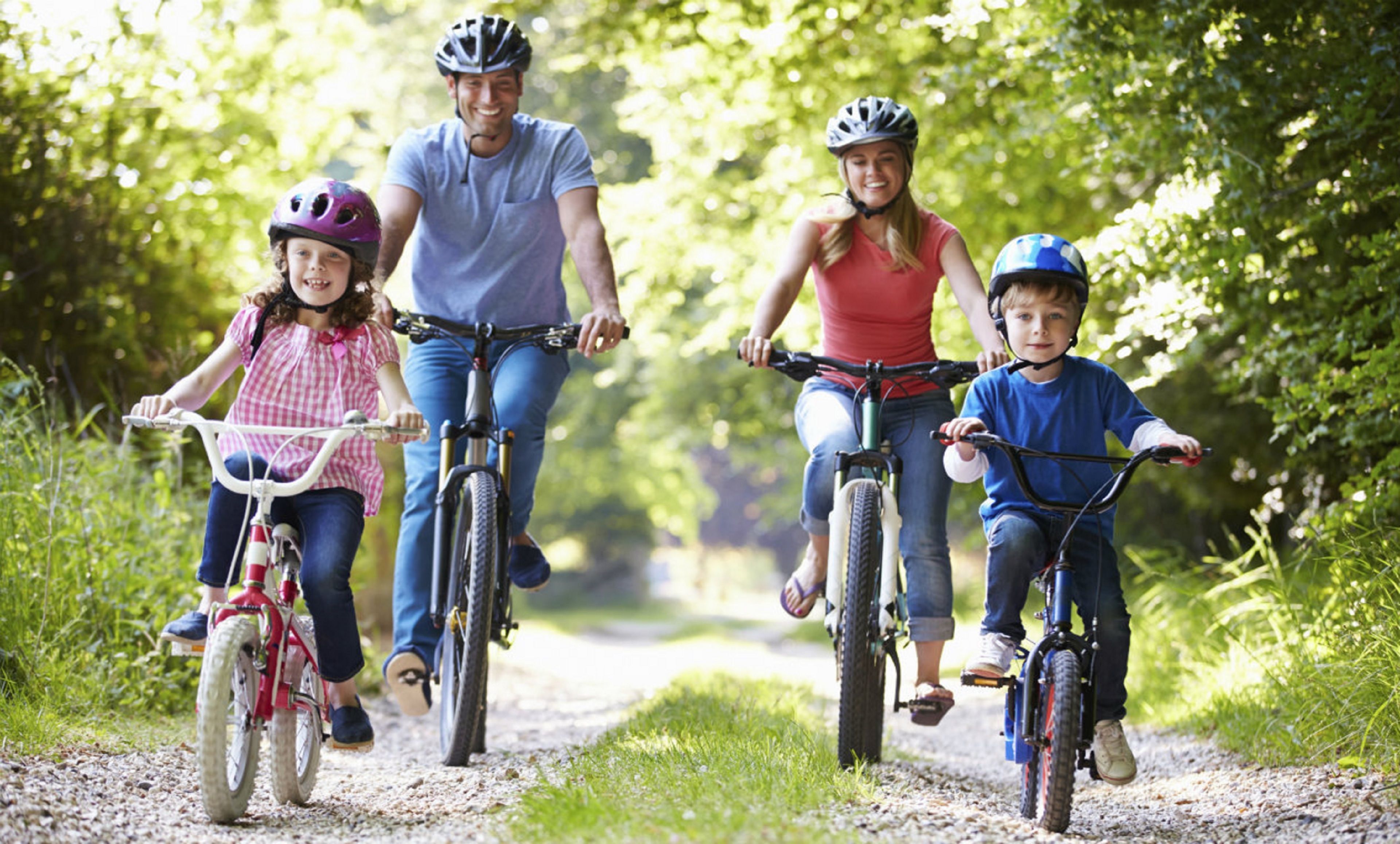 A family on a gravel path with bicycles, surrounded by greenery.
