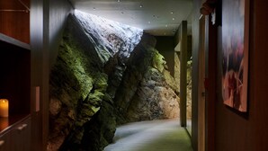 A hallway with a rock wall and a wooden floor. - Casa Andina Premium Golf Los Incas (Santiago de Surco)