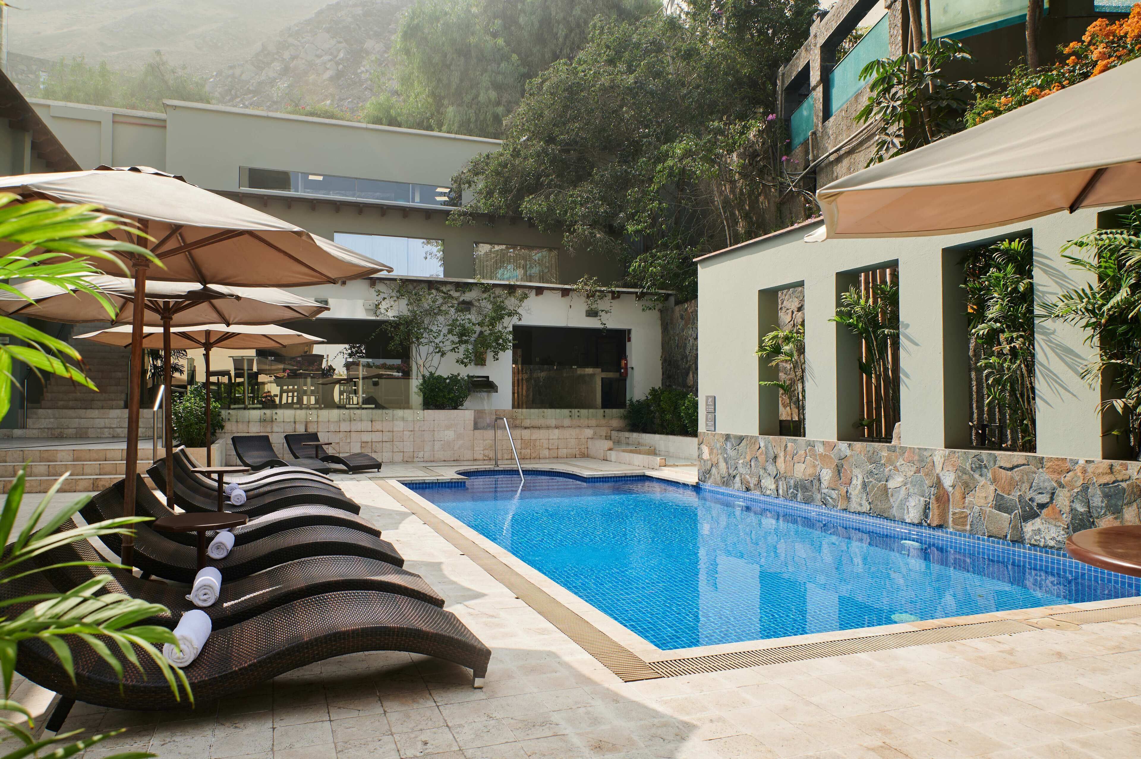 Una piscina al aire libre, sillones reclinables de piscina