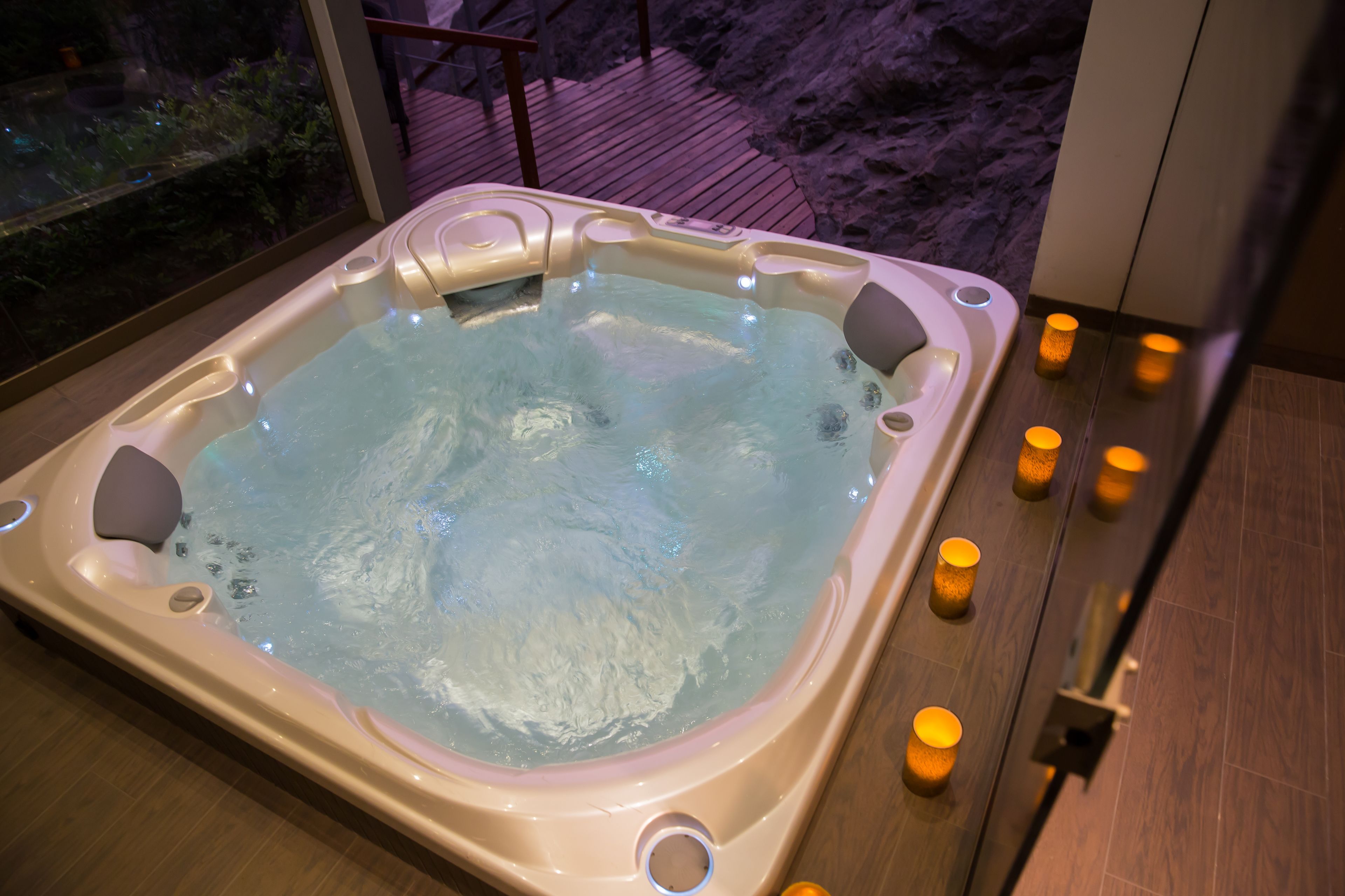Ein Whirlpool mit Holzterrasse und Kerzen.