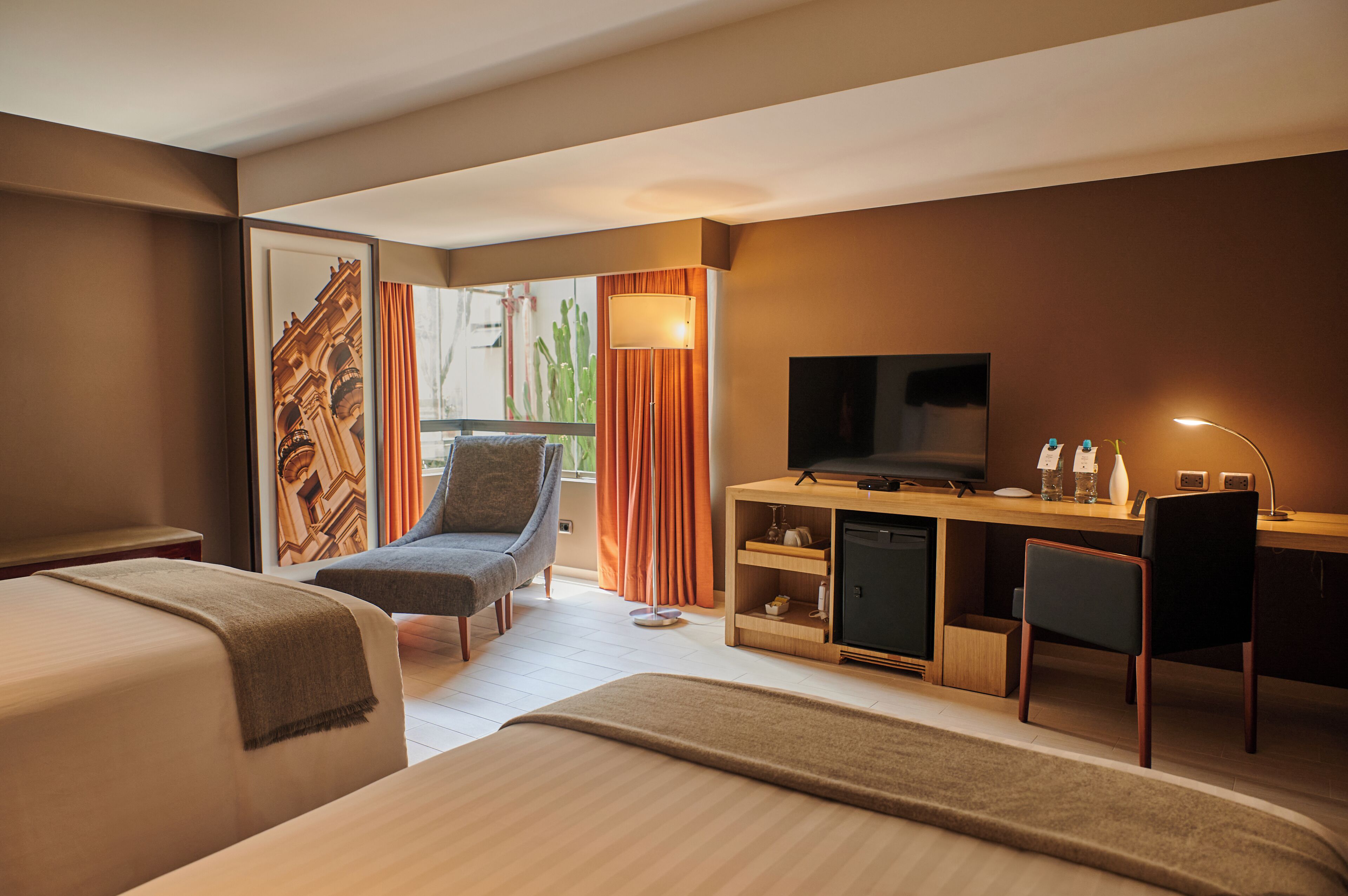 Una habitación de hotel con cama, escritorio con televisor, silla y sofá.