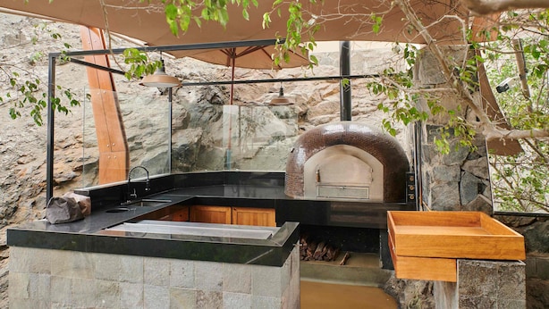 A stone-tiled outdoor kitchen area with a built-in pizza oven, a sink, and a wooden countertop. - Casa Andina Premium Golf Los Incas (Santiago de Surco)