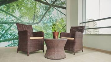 A room with two wicker chairs, a small table, and a potted plant.