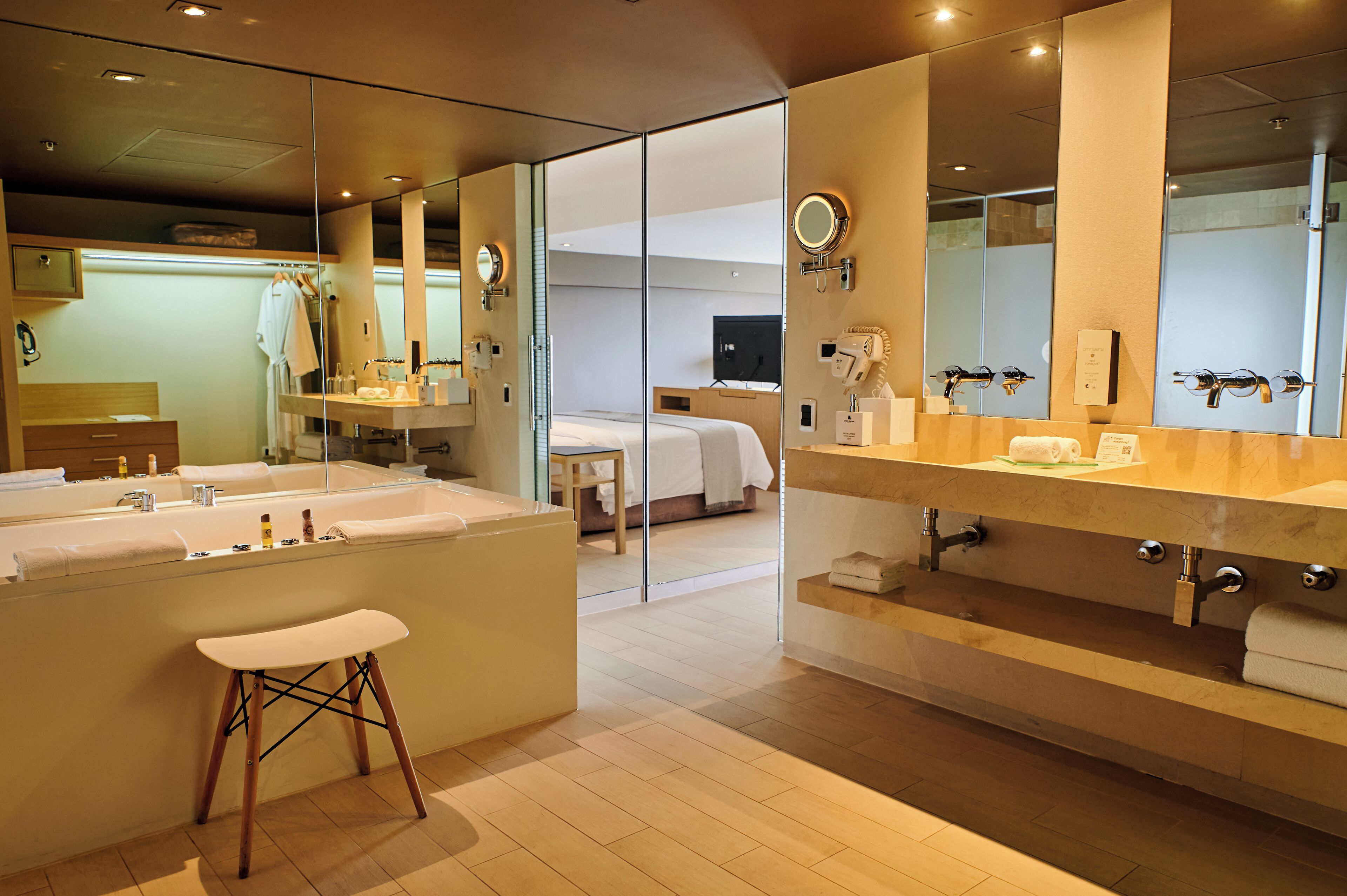 A modern bathroom with a large mirror, a bathtub, and a vanity with a sink.