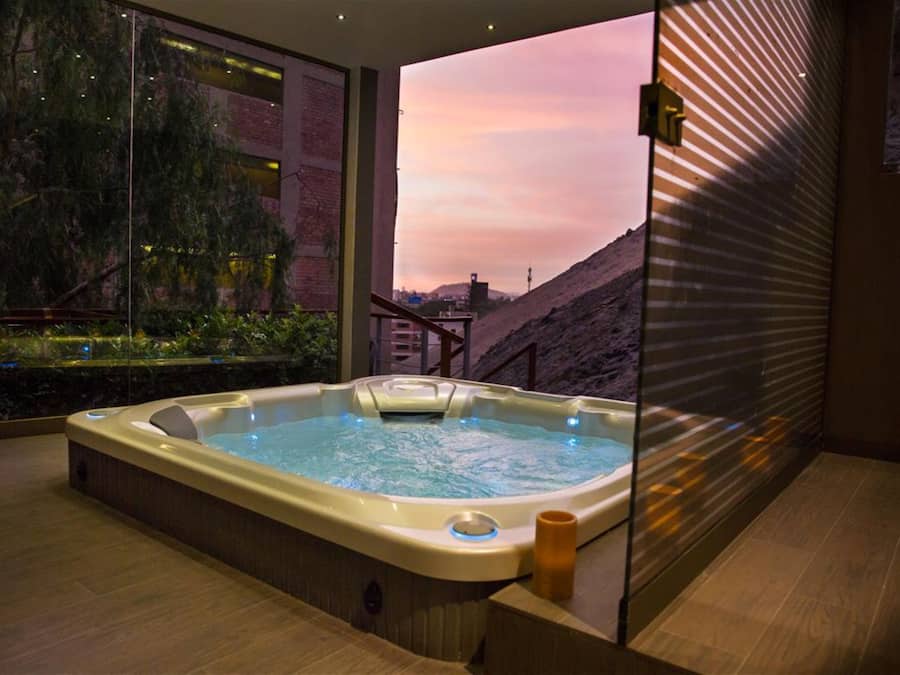 Un jacuzzi en una habitación moderna con un amplio ventanal con vistas a un paisaje montañoso.