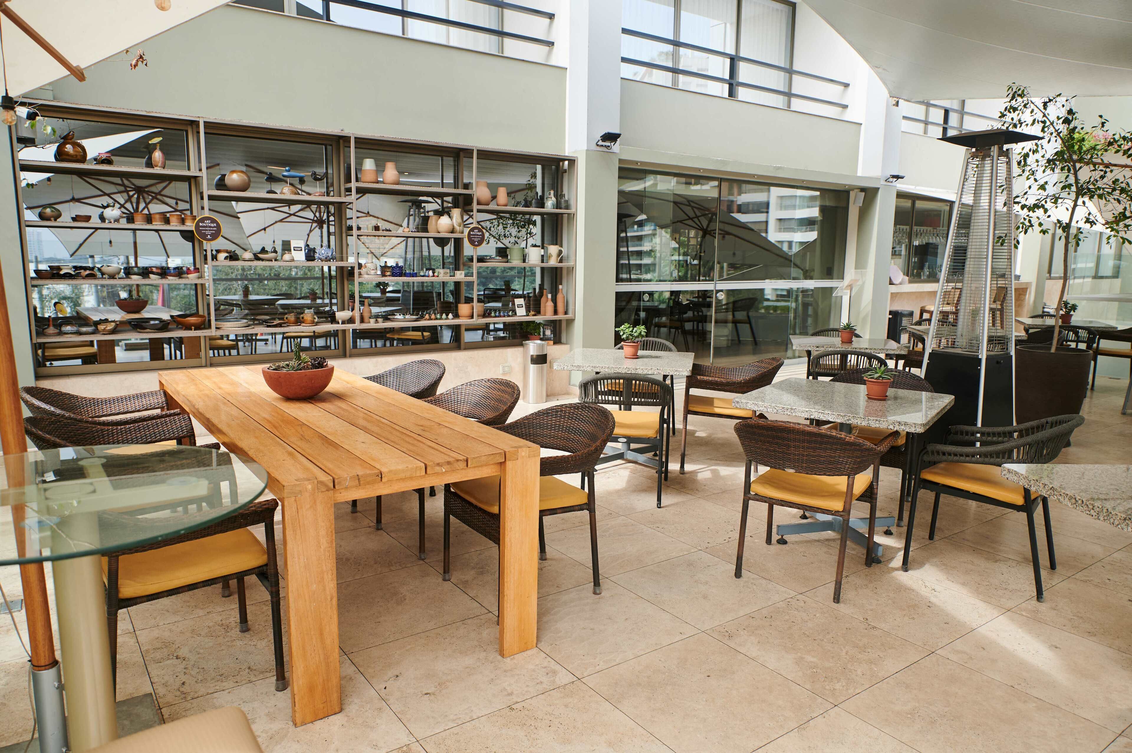 A spacious indoor area with multiple seating arrangements, including tables and chairs, and a large display of pottery and ceramics.