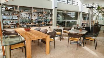 A spacious indoor area with multiple seating arrangements, including tables and chairs, and a large display of pottery and ceramics.