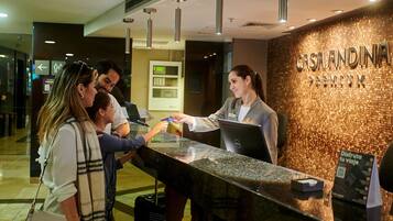 A hotel reception desk with a digital screen, a sign reading "CASA ANDINA PREMIUM," and a person at the counter.