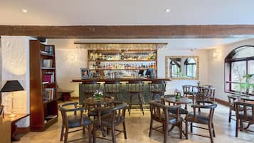 A bar area with wooden furniture, a variety of bottles, and a bookshelf.