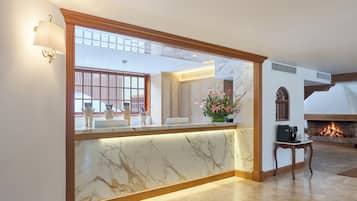 A reception area with a marble counter, a fireplace, and a view of the outside.