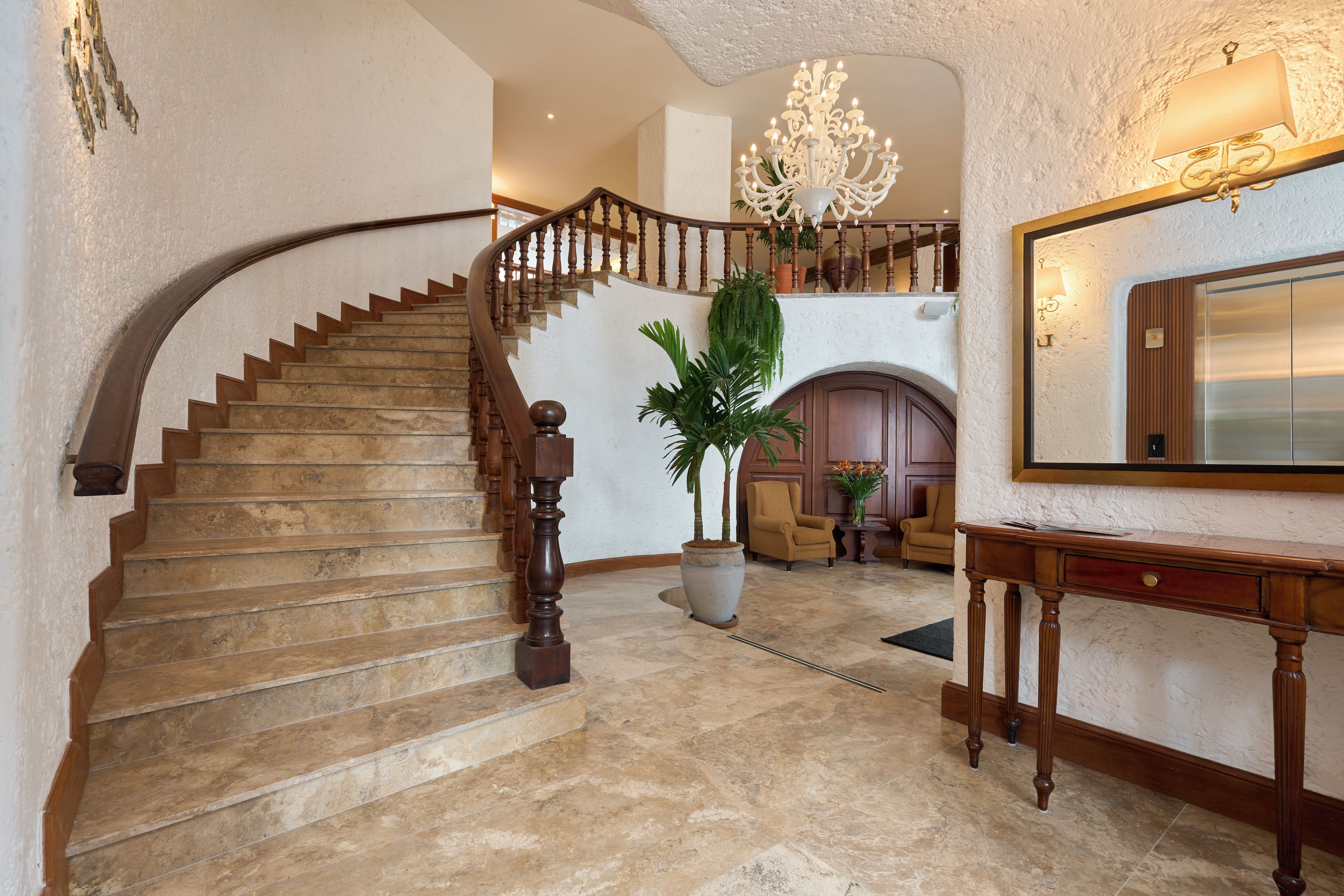 Un magnifique escalier avec une rampe en bois et un lustre au-dessus.
