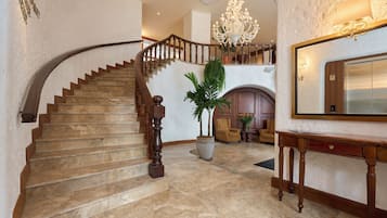 A grand staircase with a wooden handrail and a chandelier above.