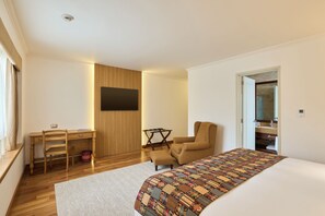 Quarto moderno com cama, escrivaninha, cadeira e televisão.