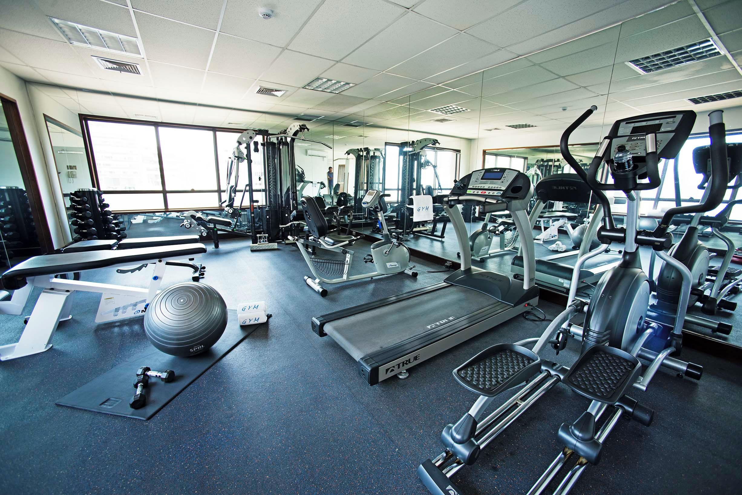 Une salle de sport équipée de divers appareils d’exercice, notamment des tapis de course, un vélo d’appartement et des poids libres.