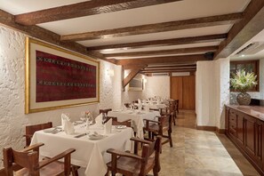 A dining area with tables set for a meal, wooden beams on the ceiling, and a large framed artwork on the wall. - La Hacienda Miraflores (Lima)