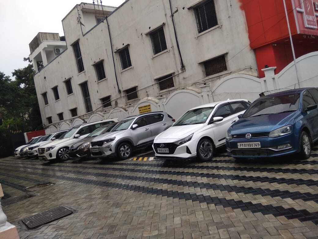 Een rij geparkeerde auto's voor een gebouw met veel ramen en een rode luifel.