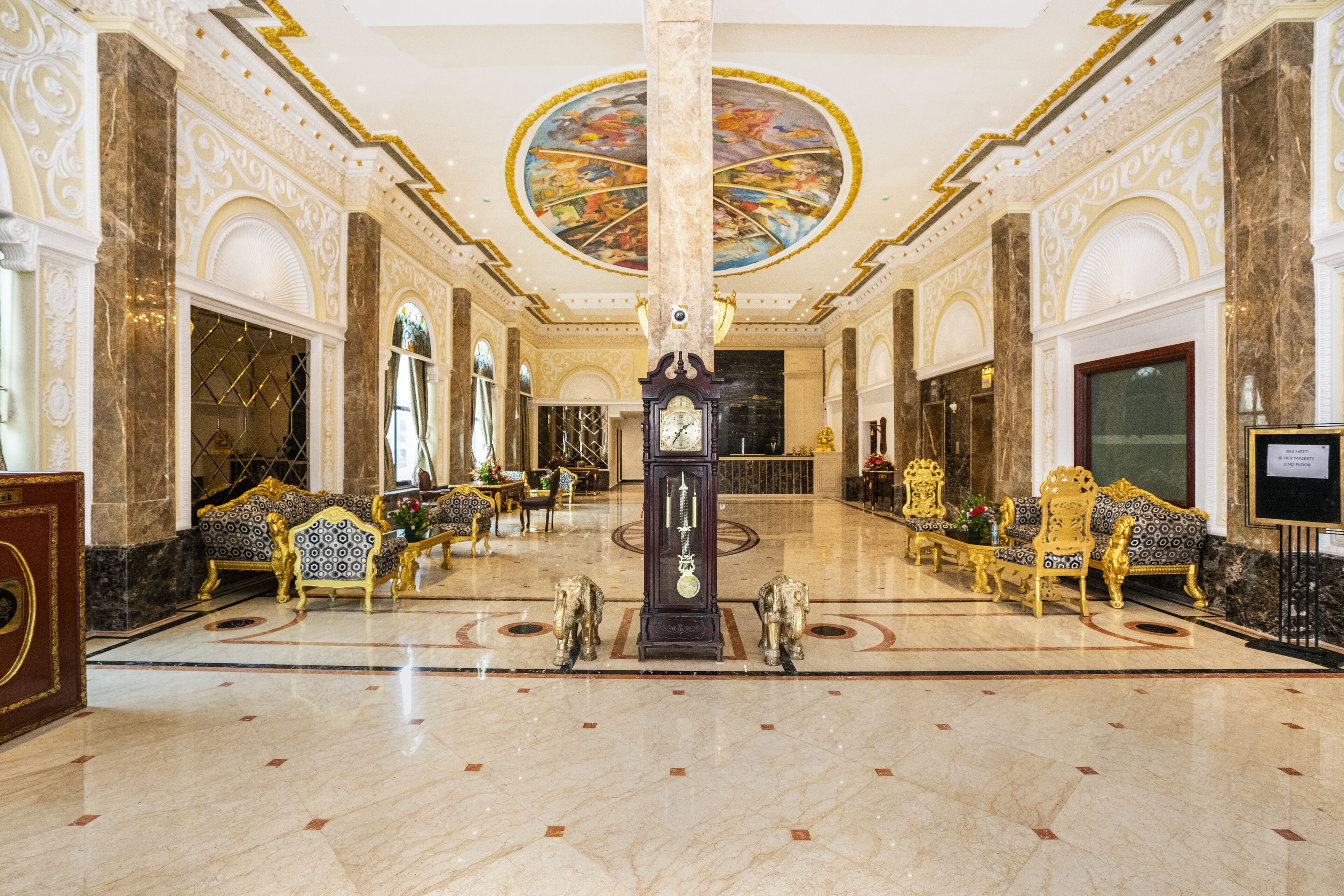 Un vestíbulo imponente con suelos de mármol, muebles ornamentados y un reloj grande.