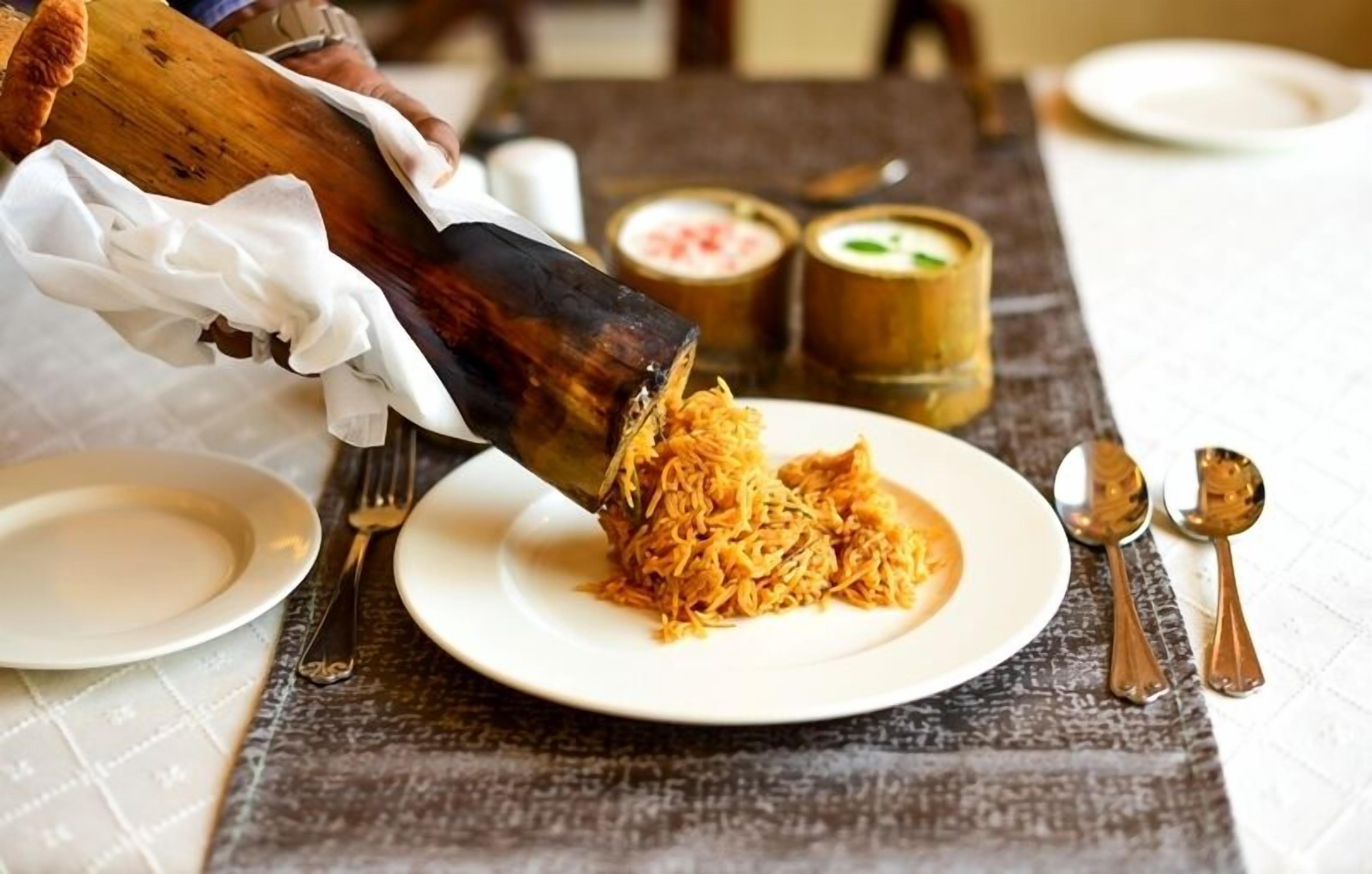 A person serving a dish from a bamboo steamer onto a plate.