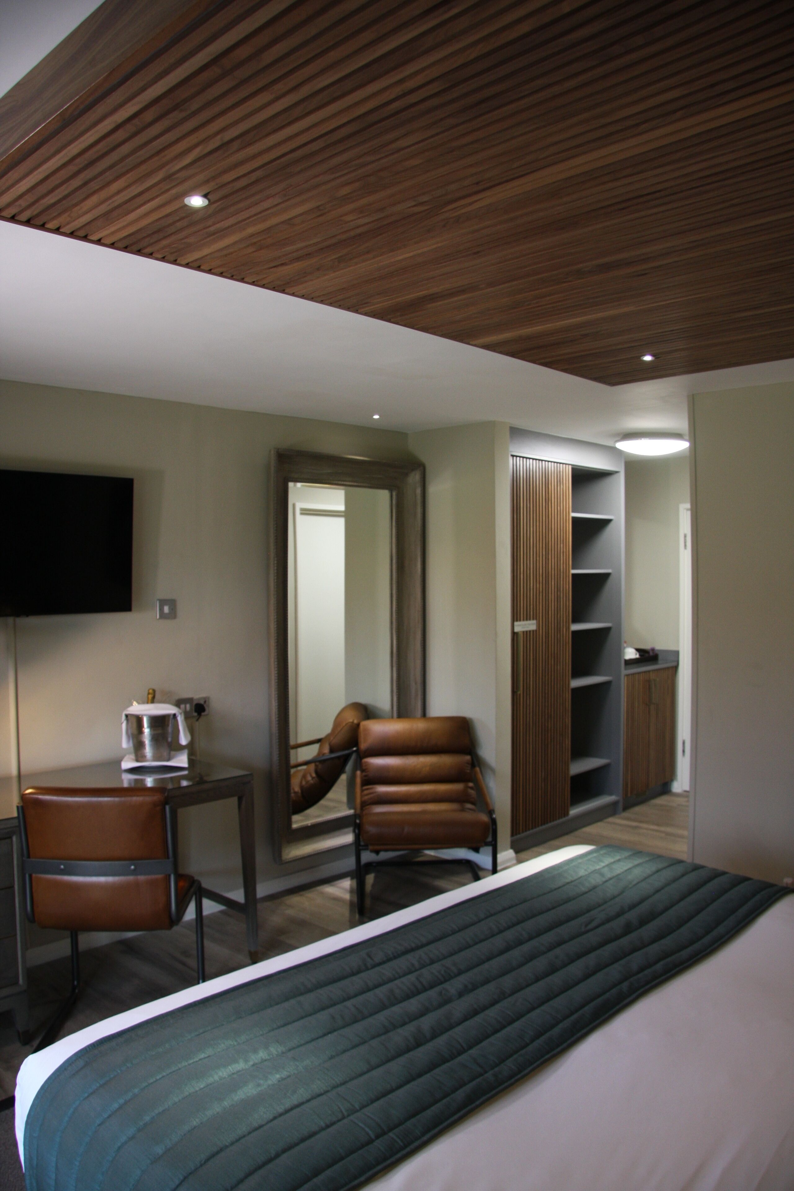 A hotel room with a bed, a desk, a chair, a television, and a wardrobe.