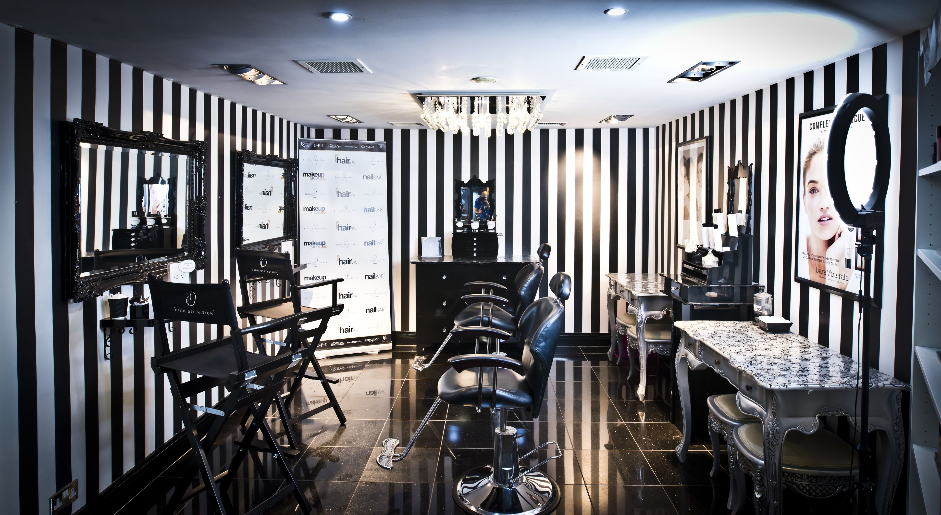 A salon with striped walls, multiple mirrors, and a chandelier.