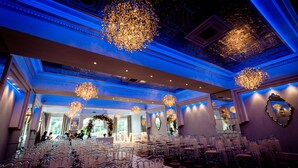 An indoor venue with rows of clear chairs, ornate chandeliers, and a decorative ceiling. - Thornton Hall Hotel and Spa (Wirral)