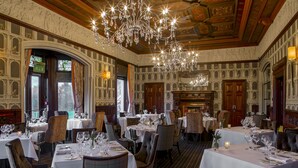 A formal dining room with multiple tables set for service, ornate chandeliers, and classical wall decorations. - Thornton Hall Hotel and Spa (Wirral)