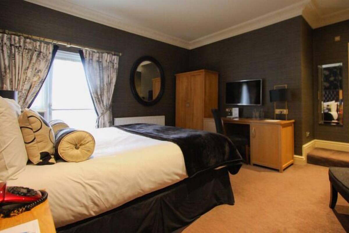 A hotel room with a bed, a desk, a television, and a wardrobe.