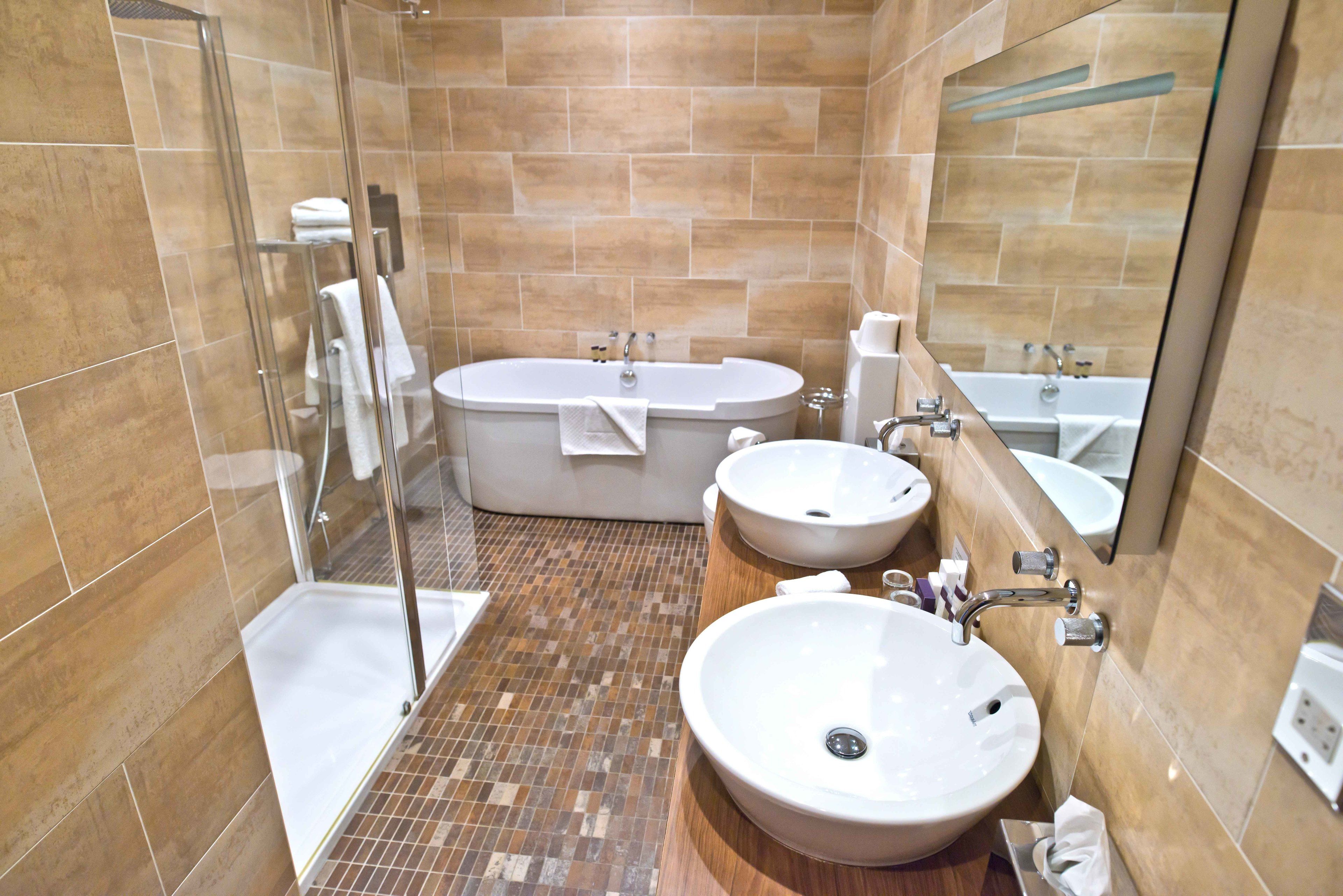 A modern bathroom with a glass-enclosed shower, a freestanding bathtub, and two sinks.