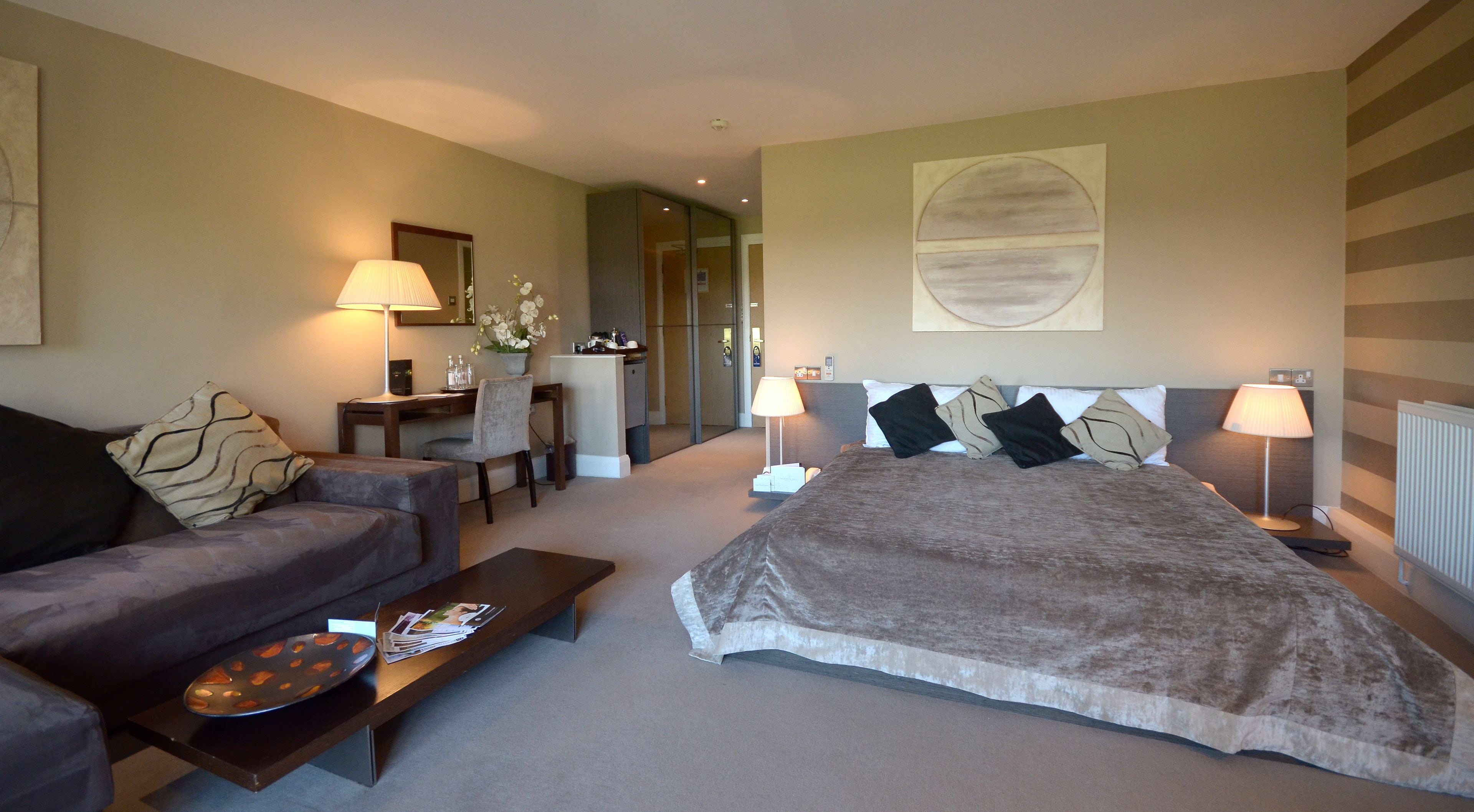 A hotel room with a bed, a sofa, a desk, and a chair.