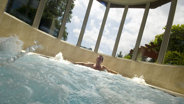 A person in a hot tub with a view of trees and a clear sky. - Thornton Hall Hotel and Spa (Wirral)
