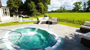 A hot tub with a water fountain, surrounded by outdoor furniture and a grassy lawn. - Thornton Hall Hotel and Spa (Wirral)
