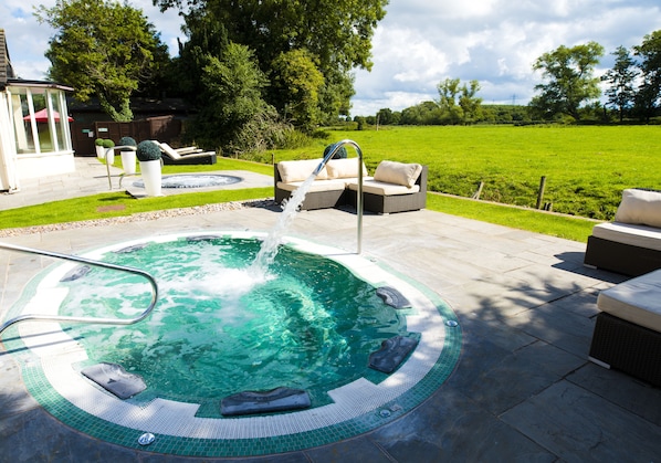 A hot tub with a water fountain, surrounded by outdoor furniture and a grassy lawn. - Thornton Hall Hotel and Spa (Wirral)