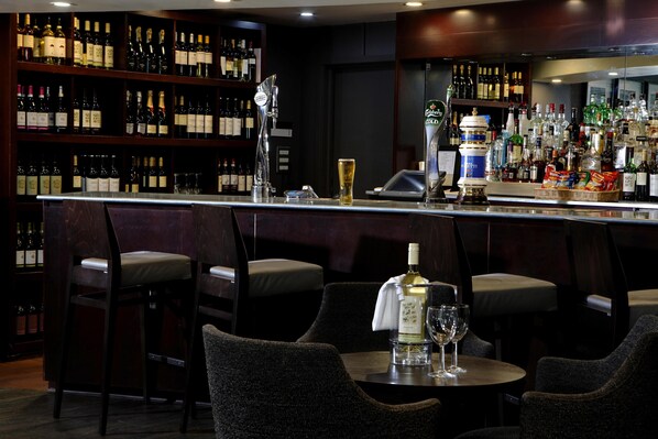 A bar area with a variety of bottles, a tap, and seating.