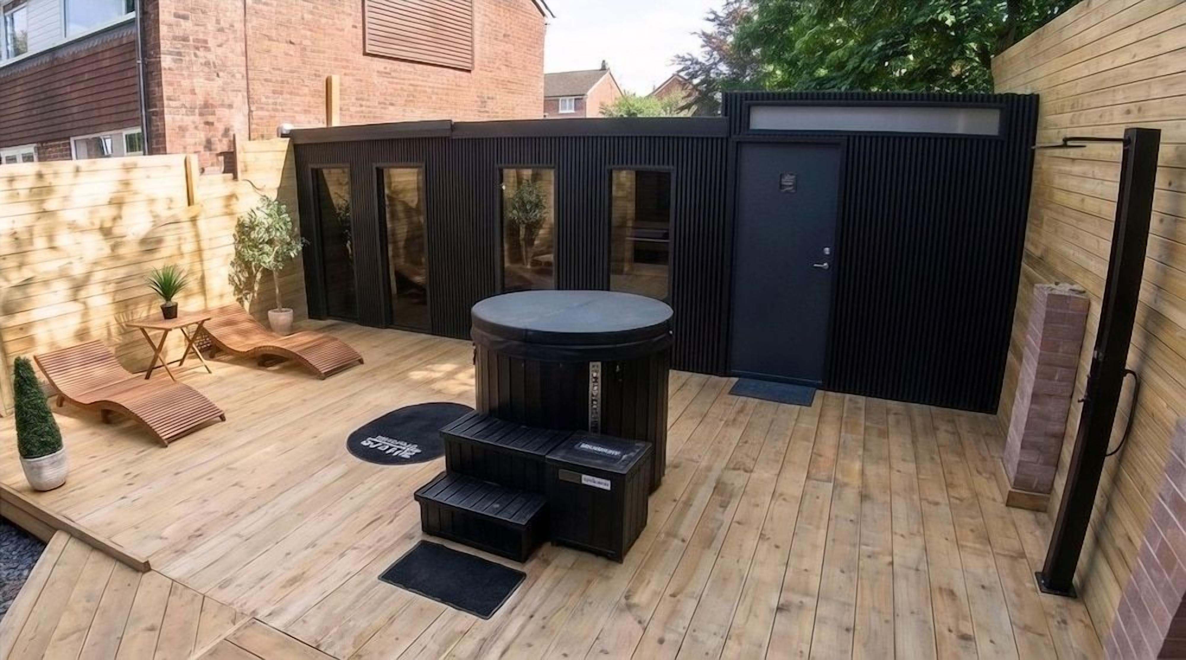 A wooden deck with a hot tub, seating area, and a small table.